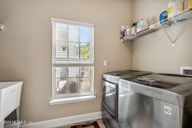 laundry area featuring laundry area, plenty of natural light, washing machine and clothes dryer, and baseboards