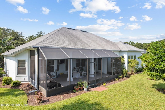 rear view of house with glass enclosure, a yard, and roof with shingles