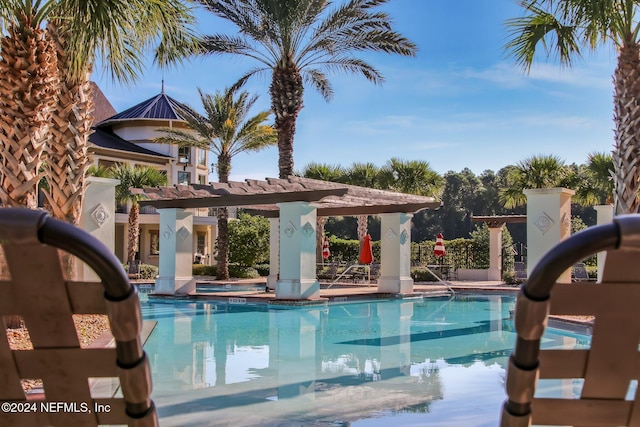 community pool with a jacuzzi, a pergola, and a water slide