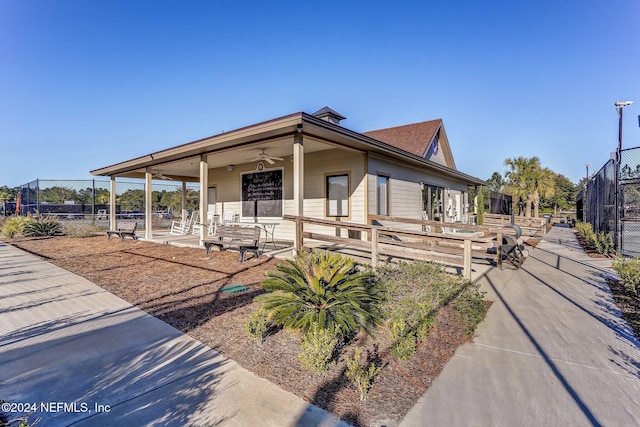 view of front of property featuring ceiling fan and fence