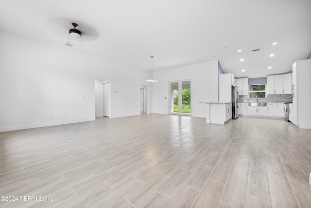 unfurnished living room featuring sink and ceiling fan