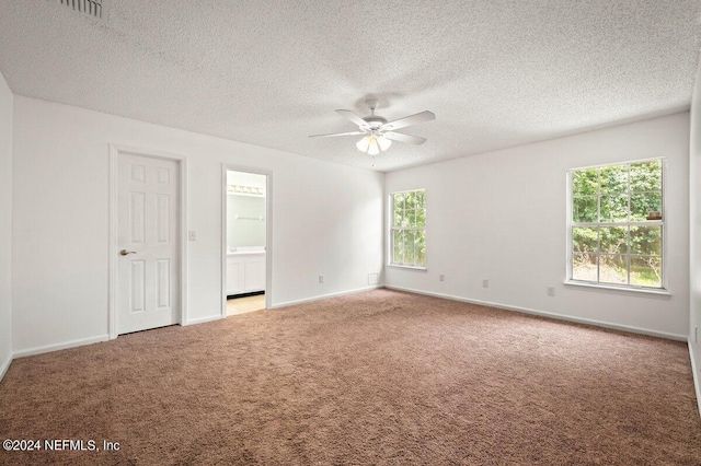 unfurnished bedroom featuring a textured ceiling, ceiling fan, multiple windows, and light colored carpet