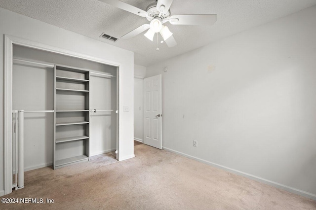 unfurnished bedroom with ceiling fan, a closet, a textured ceiling, and light colored carpet