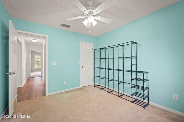 unfurnished bedroom featuring a textured ceiling, carpet flooring, and ceiling fan