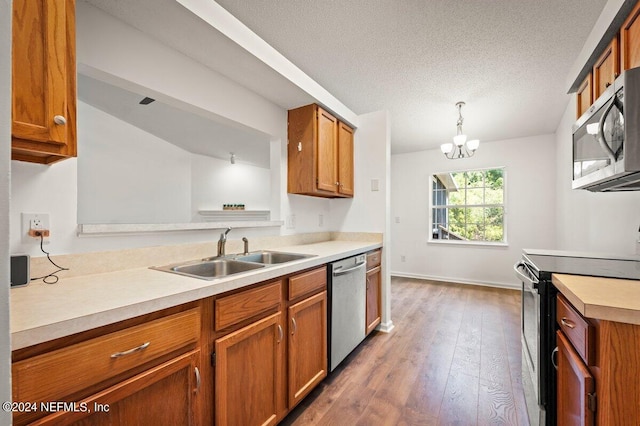 kitchen featuring dark hardwood / wood-style flooring, appliances with stainless steel finishes, sink, a notable chandelier, and decorative light fixtures