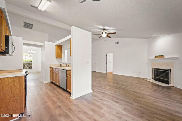 kitchen with light wood-type flooring, stainless steel dishwasher, ceiling fan with notable chandelier, lofted ceiling, and a premium fireplace