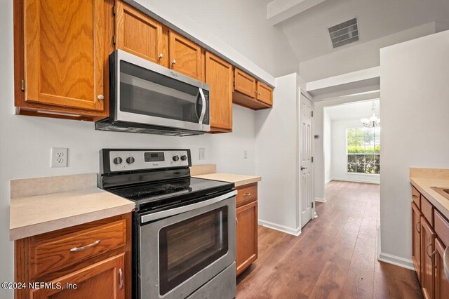 kitchen featuring appliances with stainless steel finishes, a notable chandelier, lofted ceiling with beams, and dark hardwood / wood-style floors