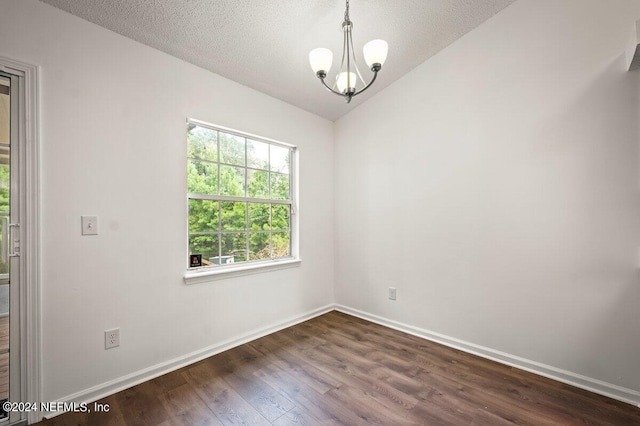 empty room with a wealth of natural light, dark hardwood / wood-style floors, and a chandelier