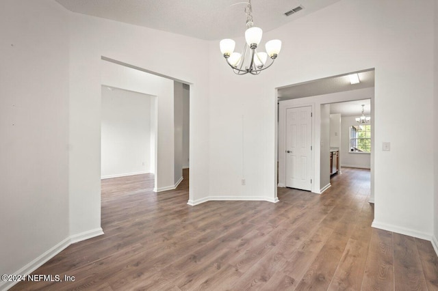 unfurnished dining area with wood-type flooring, a textured ceiling, and a chandelier