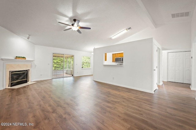 unfurnished living room featuring ceiling fan, vaulted ceiling with beams, dark hardwood / wood-style floors, a textured ceiling, and a premium fireplace