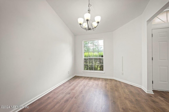 empty room featuring a notable chandelier, lofted ceiling, and hardwood / wood-style floors