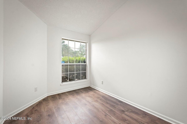 empty room with wood-type flooring, a textured ceiling, and lofted ceiling