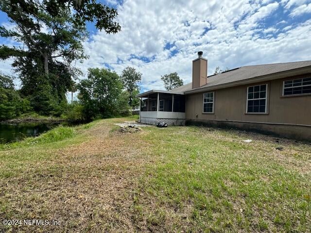 back of house featuring a yard and a sunroom