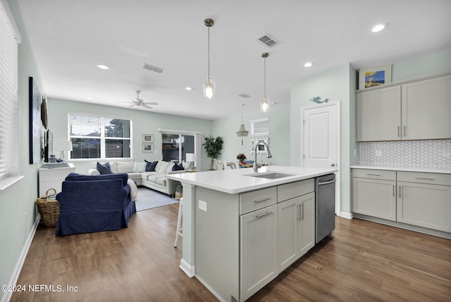 kitchen with sink, wood-type flooring, a kitchen island with sink, stainless steel dishwasher, and tasteful backsplash