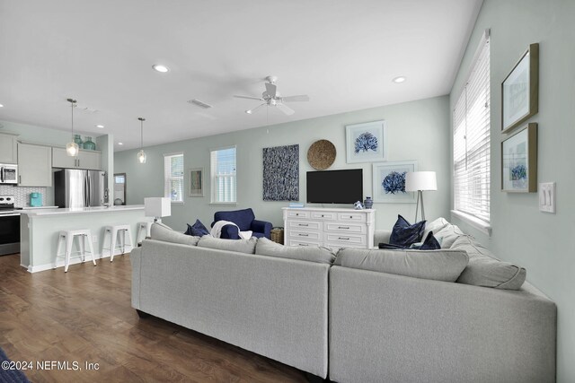 living room featuring plenty of natural light, ceiling fan, and dark hardwood / wood-style floors