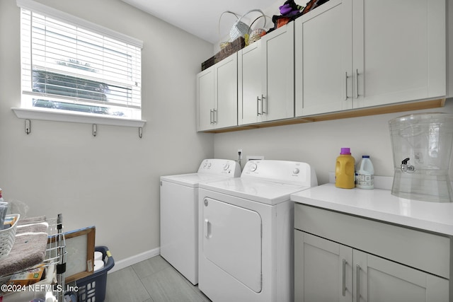 washroom with independent washer and dryer, light tile patterned floors, and cabinets