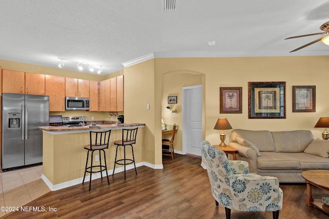 kitchen featuring arched walkways, a breakfast bar area, appliances with stainless steel finishes, open floor plan, and a peninsula