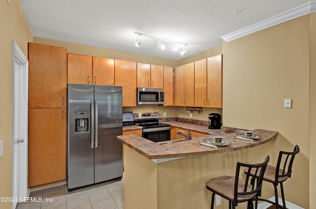 kitchen featuring light tile patterned floors, a breakfast bar area, appliances with stainless steel finishes, a peninsula, and a sink