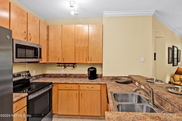 kitchen with sink, light tile patterned flooring, a textured ceiling, stainless steel appliances, and crown molding