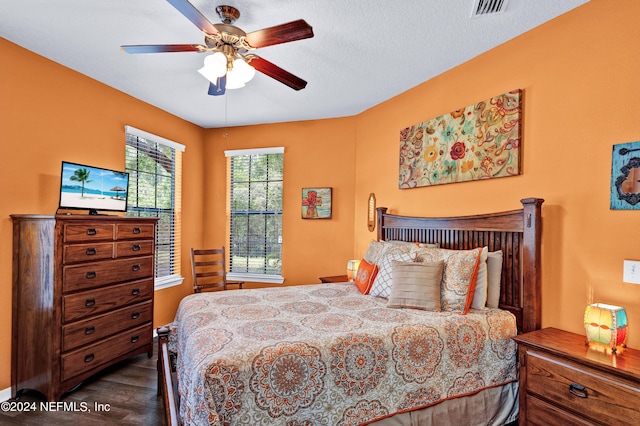 bedroom with dark wood-style flooring, visible vents, ceiling fan, and a textured ceiling