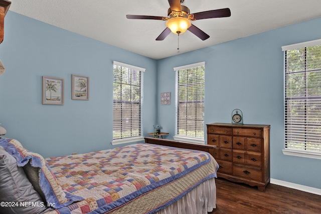 bedroom with multiple windows, dark wood finished floors, a ceiling fan, and baseboards