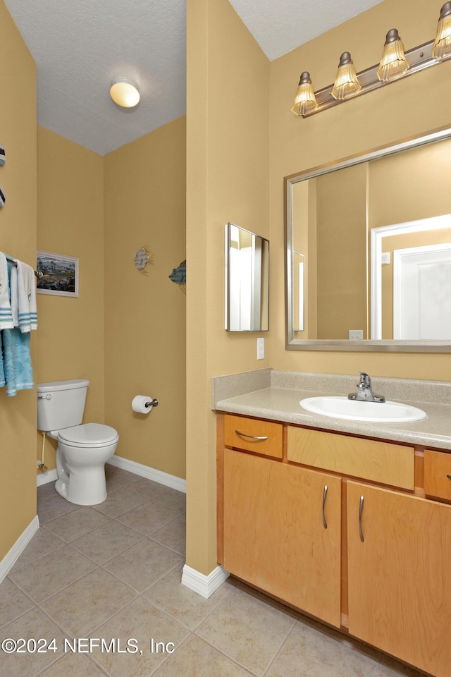 bathroom with toilet, baseboards, and tile patterned floors