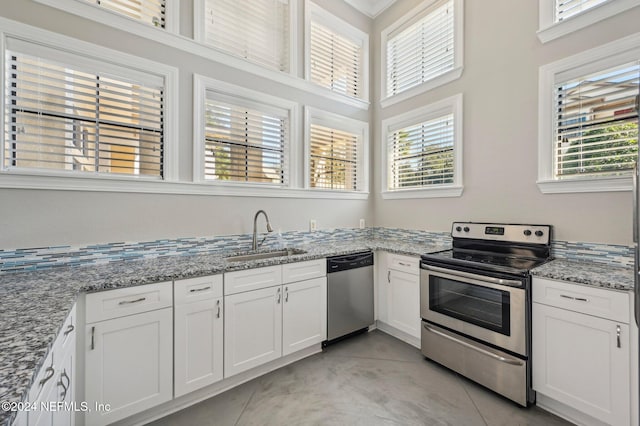 kitchen featuring light stone counters, appliances with stainless steel finishes, white cabinets, and a sink