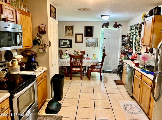 kitchen featuring light tile patterned floors, stainless steel appliances, and a textured ceiling