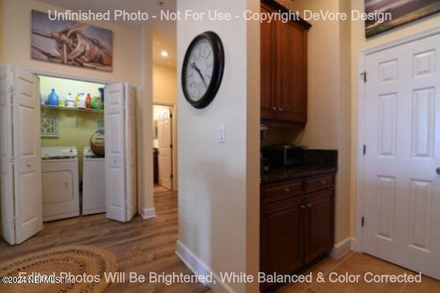 kitchen featuring dark countertops, light wood finished floors, baseboards, and washer and clothes dryer