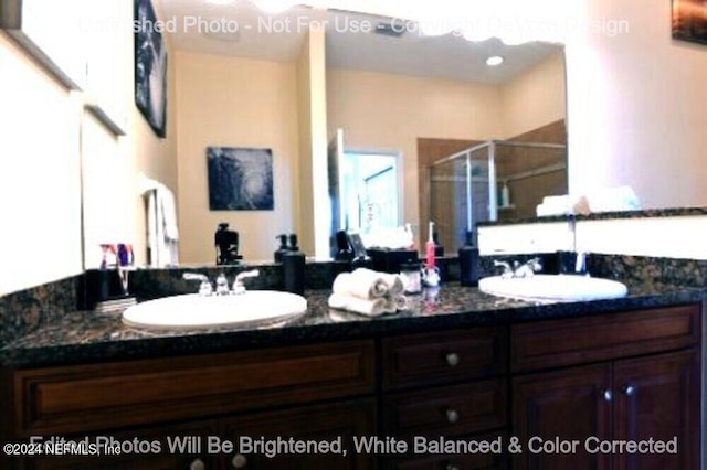 bathroom with a stall shower, a sink, and double vanity