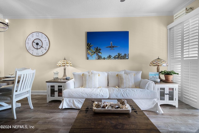 living area featuring baseboards, a textured ceiling, ornamental molding, and wood finished floors