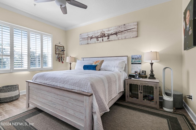 bedroom featuring ceiling fan, ornamental molding, wood finished floors, and baseboards