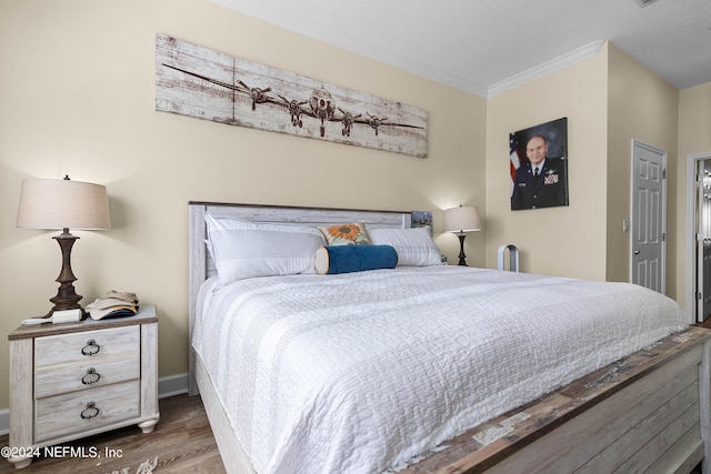 bedroom with crown molding, baseboards, and wood finished floors