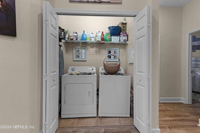 laundry room featuring laundry area, baseboards, washing machine and clothes dryer, and wood finished floors