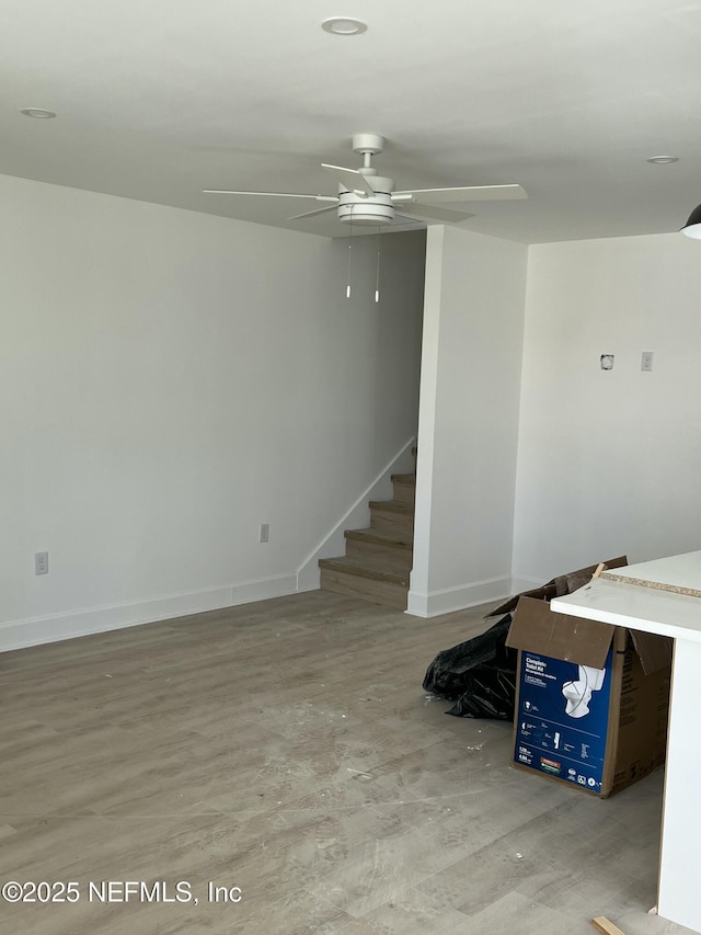 interior space featuring baseboards, stairway, and ceiling fan