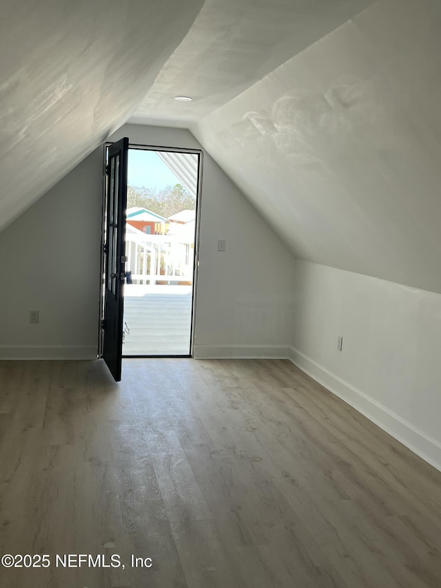 bonus room featuring lofted ceiling, baseboards, and wood finished floors