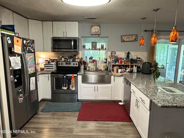 kitchen featuring appliances with stainless steel finishes, plenty of natural light, and white cabinets