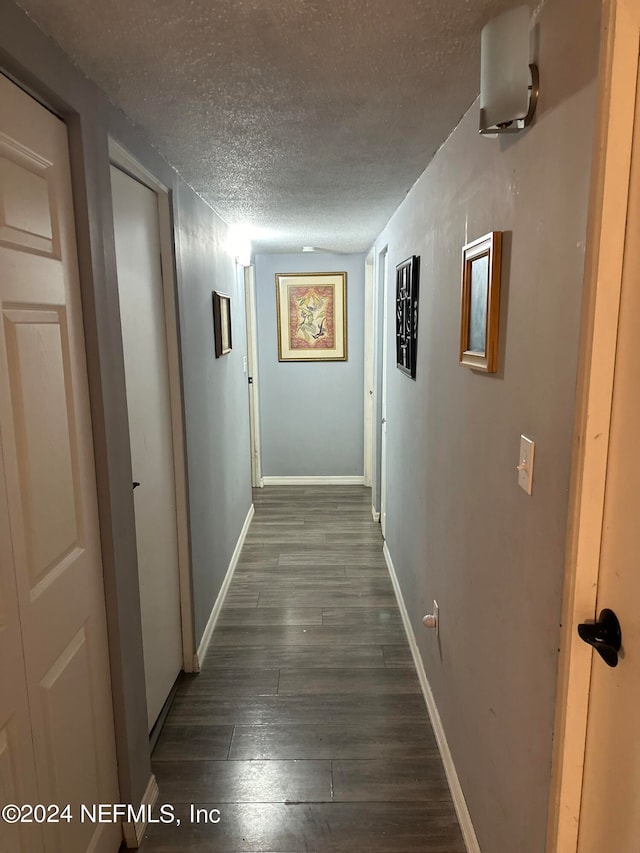 corridor featuring a textured ceiling and dark wood-type flooring