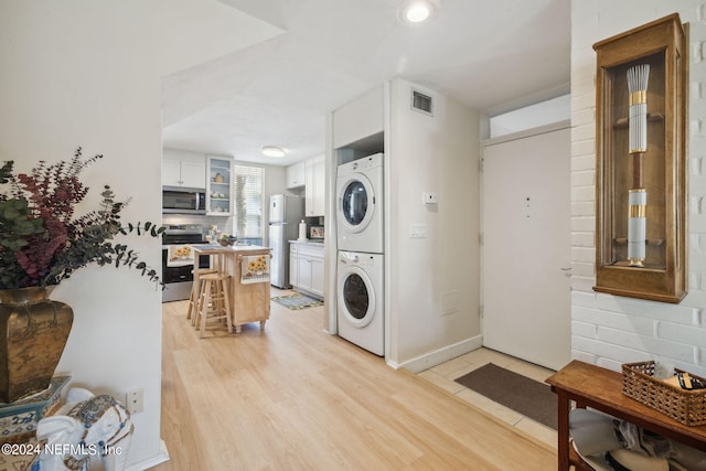 laundry area featuring light hardwood / wood-style flooring and stacked washer / drying machine