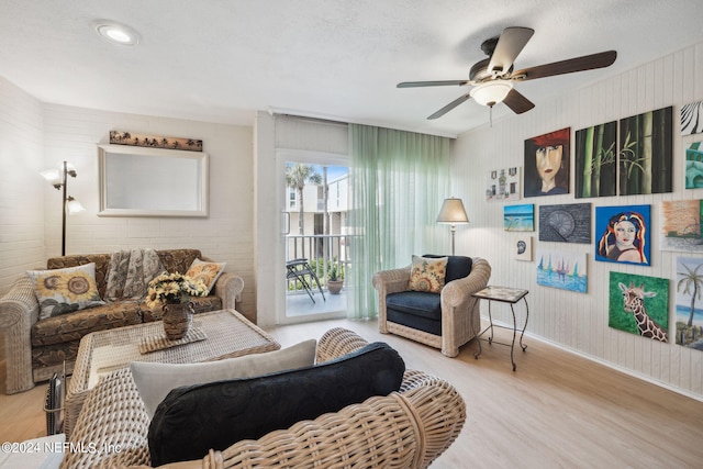 living room featuring a textured ceiling, light hardwood / wood-style flooring, and ceiling fan