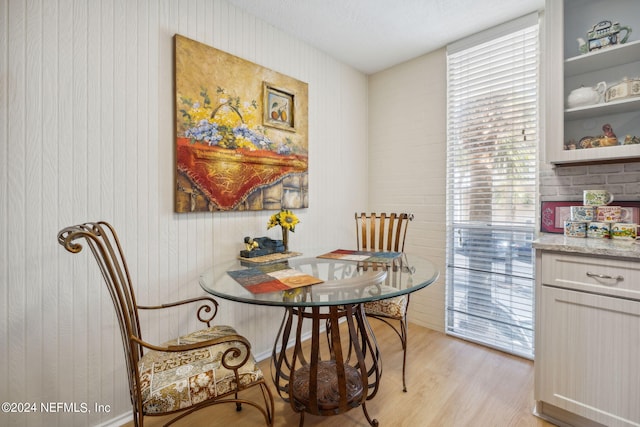 dining room featuring a textured ceiling, wood walls, and light wood-type flooring