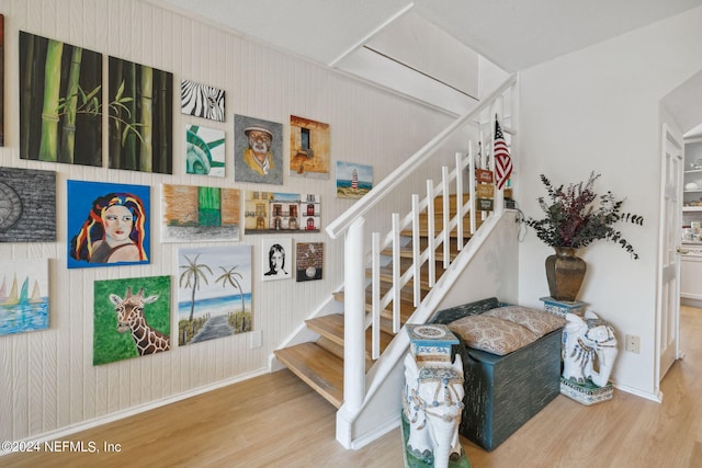 staircase with hardwood / wood-style flooring and wooden walls