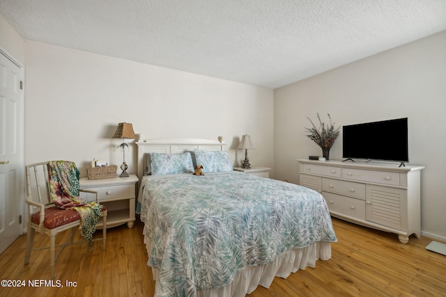 bedroom with a textured ceiling and light wood-type flooring