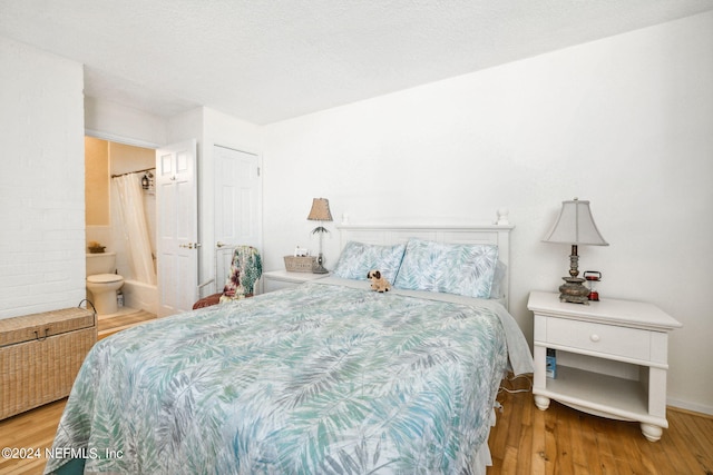 bedroom featuring a textured ceiling, connected bathroom, a closet, and hardwood / wood-style flooring