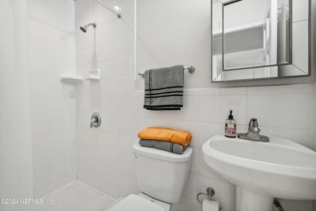 bathroom with backsplash, tiled shower, tile walls, toilet, and sink