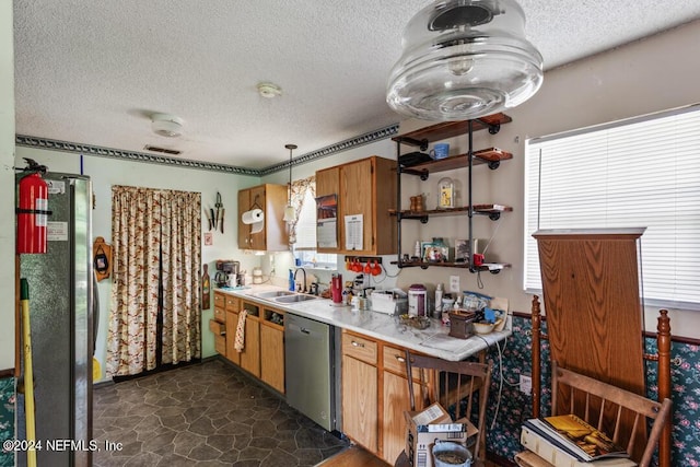 kitchen with brown cabinetry, a sink, stainless steel appliances, light countertops, and a textured ceiling