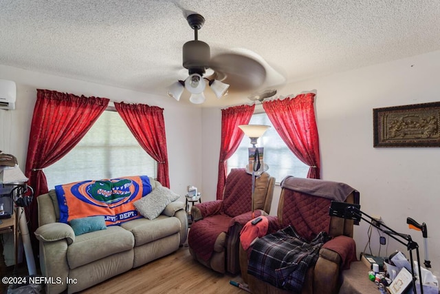 living room featuring plenty of natural light, a textured ceiling, wood finished floors, and a ceiling fan