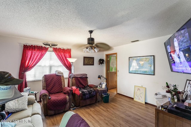 living room featuring visible vents, a textured ceiling, ceiling fan, and wood finished floors