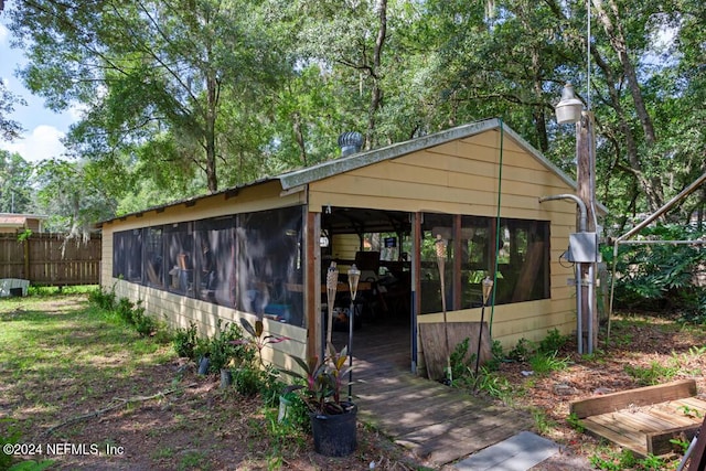 view of outbuilding featuring a sunroom and fence