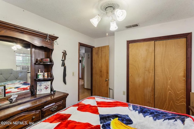 bedroom featuring a ceiling fan, visible vents, a closet, and a textured ceiling